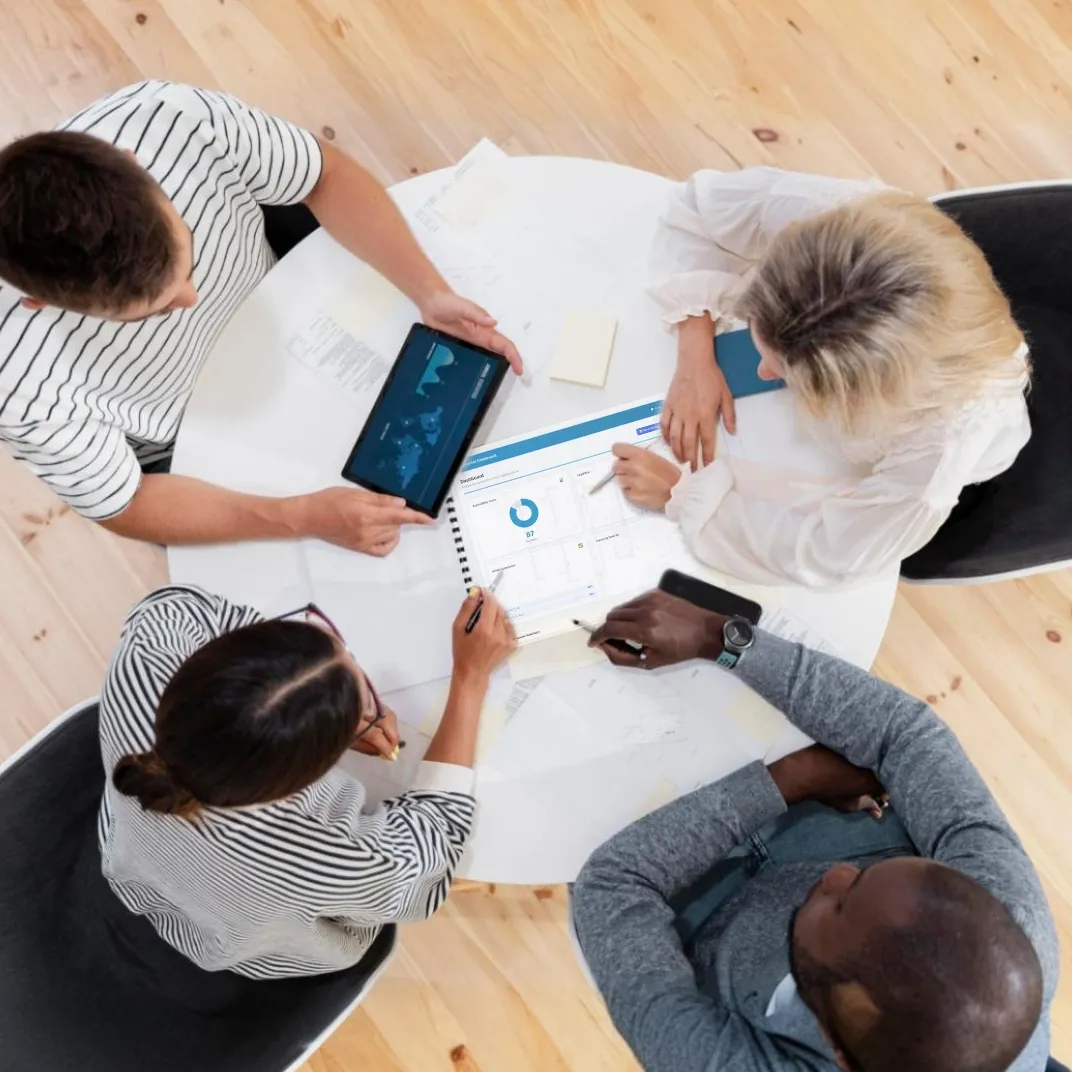 Team discussing documents and analyzing global data on a tablet during a meeting.